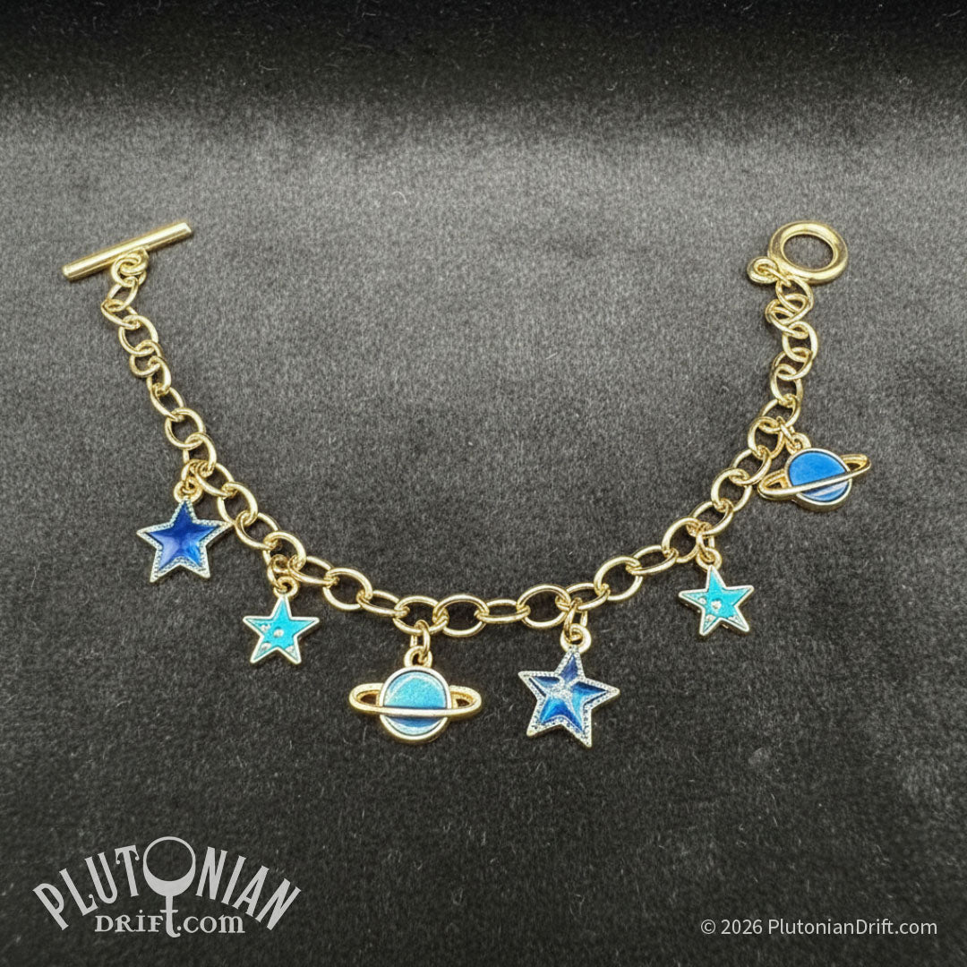 Travel Guide - Galactic tour charm bracelet. A gold tone chain charm bracelet against a grey velvet background. Charms are blue enamel stars and ringed planets. Plutonian Drift.